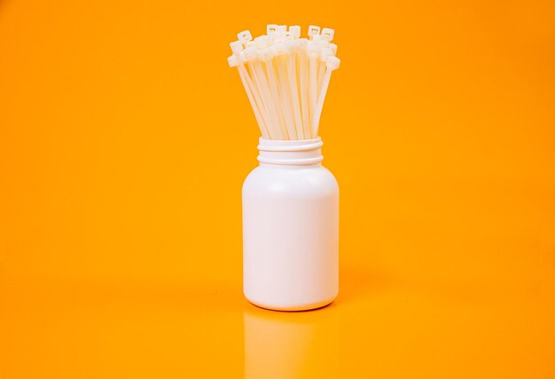 Nylon cable ties in glass in jar in bucket on orange background