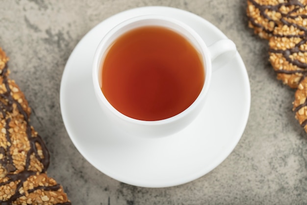 Oat chocolate biscuits with cup of black tea on stone.