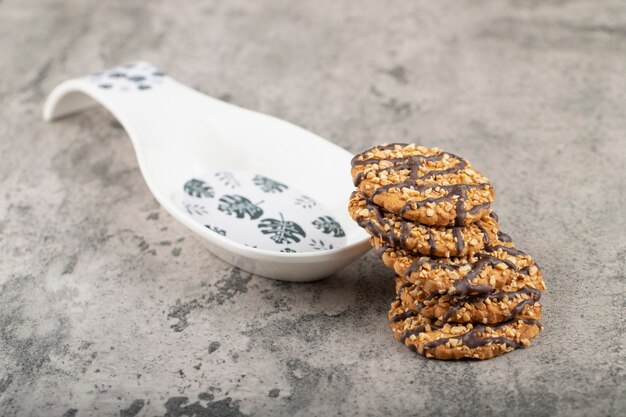 Photo oat chocolate biscuits with nuts placed next to ceramic spoon.