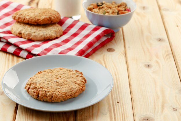 Oat cookies and oat flakes on wooden surface