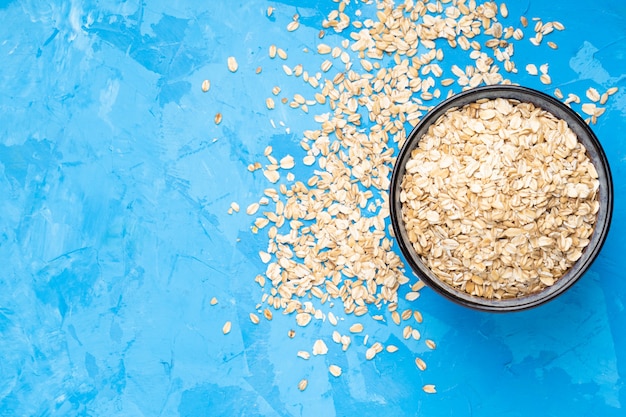 Fiocchi d'avena in un piatto blu su uno sfondo di cemento blu.