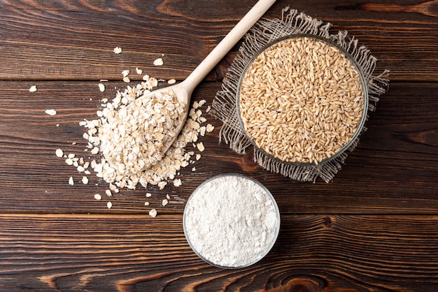 Oat flakes and flour on dark wood.