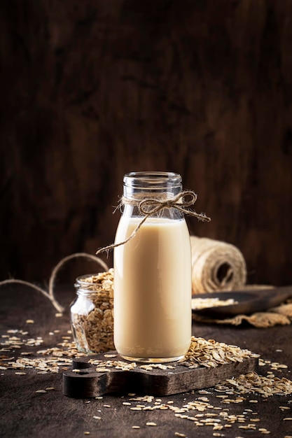 ガラスの木製の素朴なキッチンテーブルのコピースペースでオーツ麦フレークミルク非乳製品代替植物ベースの飲み物