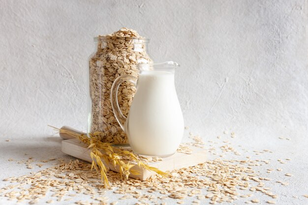 Oat flakes, out milk on a table. Plant-based healthy and vegetarian eating and drink. Selective focus, close up