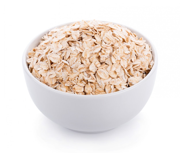 Oat flakes pile in white bowl on white wall