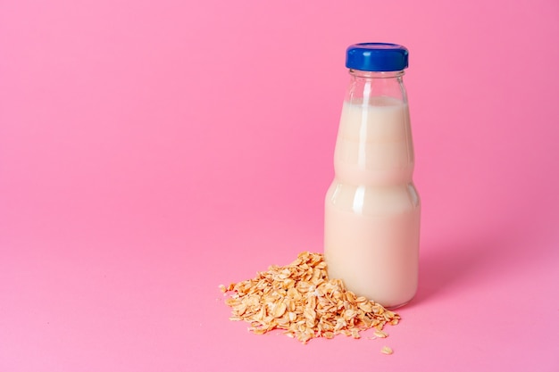 Oat milk in glassware and dry oat flakes