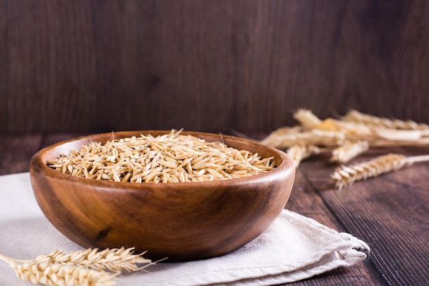 Oat seeds in a wooden bowl and ears on the table Organic harvest