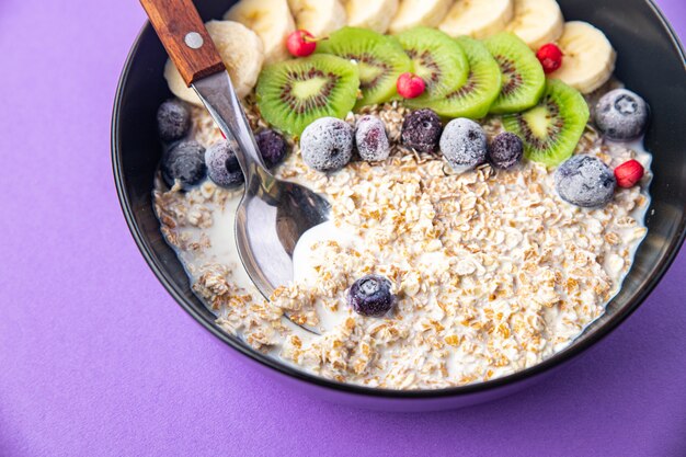 Oatmeal bowl fruit banana kiwi berries blueberries ready to eat meal snack on the table