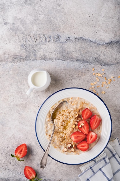 Oatmeal Bowl of oatmeal porridge with strawberry almond and milk on vintage light grey teal table Top view in flat lay style Natural ingredients Hot and healthy breakfast and diet food