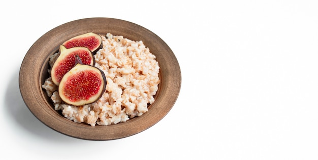 Farina d'avena in una ciotola con fichi freschi, mandorle e anacardi su un tavolo luminoso. farina d'avena con frutta. cibo sano. cibo per la perdita di peso. dieta. copia spazio. vista laterale.