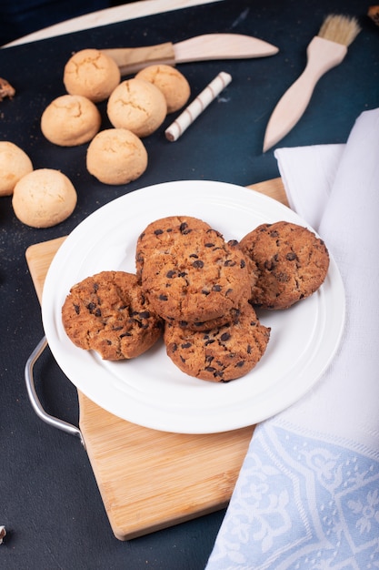 Photo oatmeal and butter cookies with chocolate chips on a wooden board