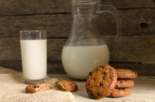 Oatmeal chocolate chip cookies jug and glass of milk rustic wooden background Country dinner