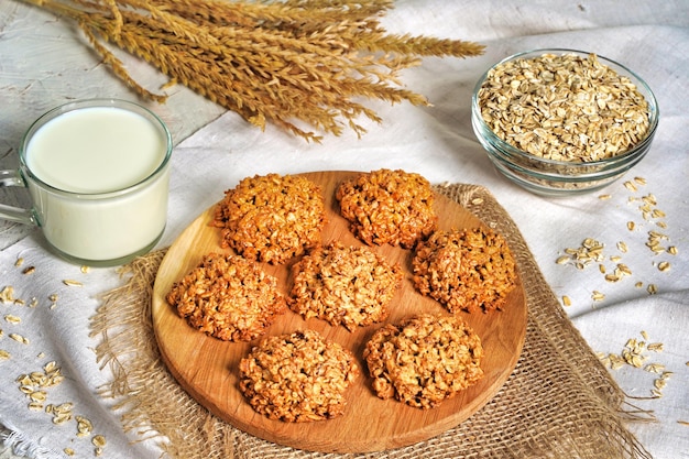 Oatmeal cookies close up view Stack of homemade delicious rolled oats cookies on table napkin oat flakes and milk bottle Morning breakfast table background High quality photo