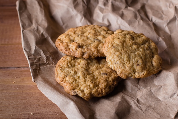 Oatmeal cookies on kraft paper on wooden table background. 