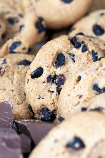 Oatmeal cookies and large pieces of sweet chocolate together, cookies with chocolate pieces inside, close-up food for desserts