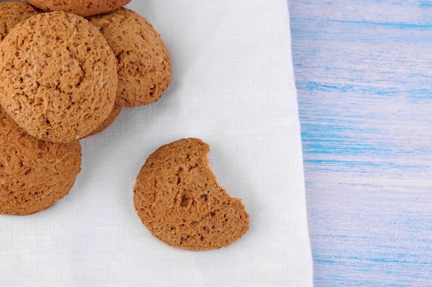 푸른 나무 테이블에 흰색 냅킨에 쌓여 있는 오트밀 쿠키. 빵 굽기. 아주 맛있는.