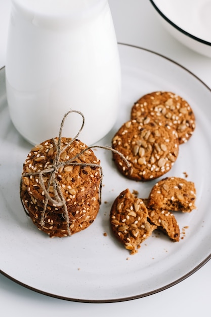 Photo oatmeal cookies with a carafe of milk on a white plate