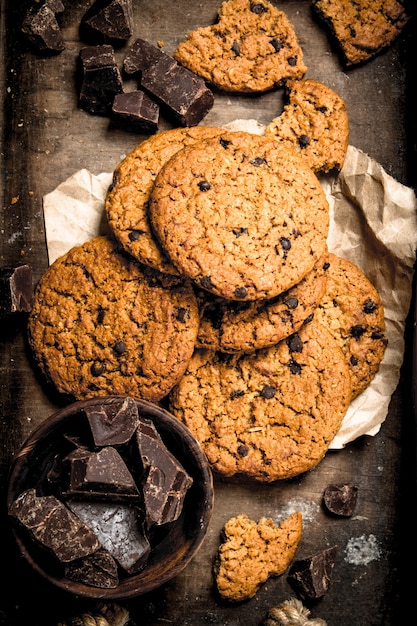 Oatmeal cookies with chocolate in a bowl. On a rustic background.