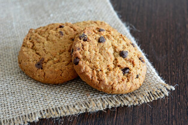 Photo oatmeal cookies with chocolate isolated on the burlap texture close up