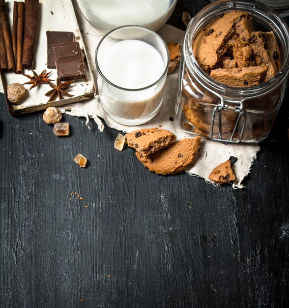 Oatmeal cookies with fresh milk. On a black wooden table.