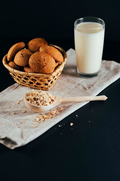 Oatmeal cookies with a glass of milk on a napkin on a black background The concept of a healthy breakfast