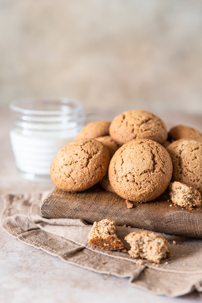 Oatmeal cookies on wooden cutting board with a cup of milk Healthy snack or dessert