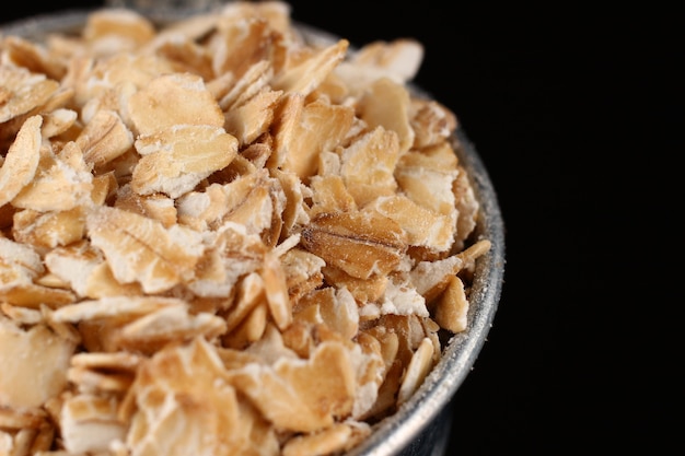 Oatmeal flakes in a bucket on a dark background