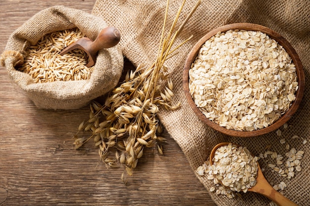 Oatmeal flakes grains and ears of oat on wooden table