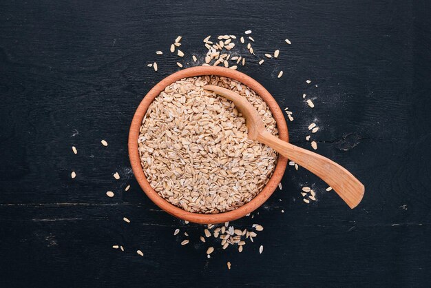 Oatmeal flakes in a plate on a wooden background Top view Copy space