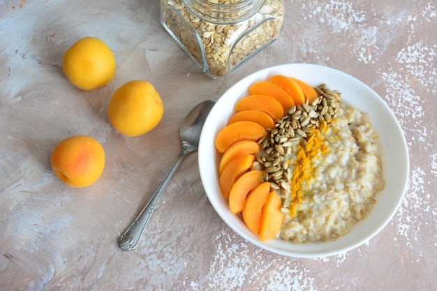 Oatmeal flakes with apricot slices, sunflower seeds and curcuma on beige background