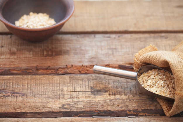 Oatmeal or oat flakes on wooden table.