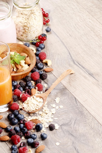 Oatmeal oats with berries nuts orange juice and yogurt on wooden table