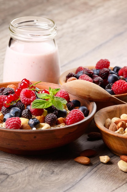 Овсяная каша с ягодами, орехами и йогуртом на деревянном столе