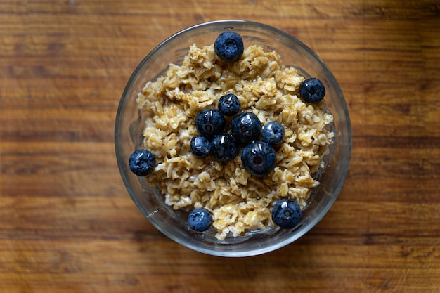 Oatmeal porridge in bowl with blueberries on a wooden table background healthy breakfast food.