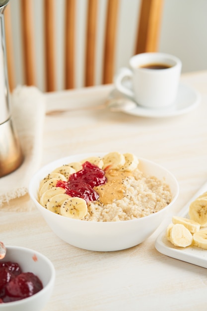 Oatmeal porridge, healthy vegan diet breakfast with strawberry jam, peanut butter, banana, 