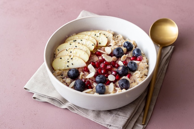 Oatmeal porridge with apple, pomegranate, blueberries and almonds. Healthy eating. Vegetarian food. Breakfast.