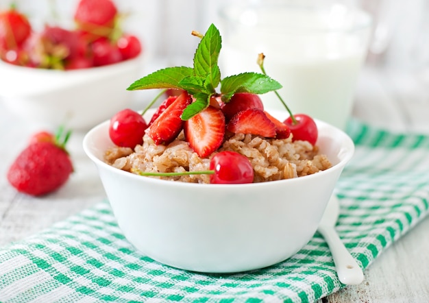 Oatmeal porridge with berries in a white bowl