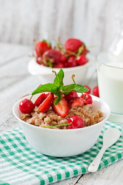 Oatmeal porridge with berries in a white bowl