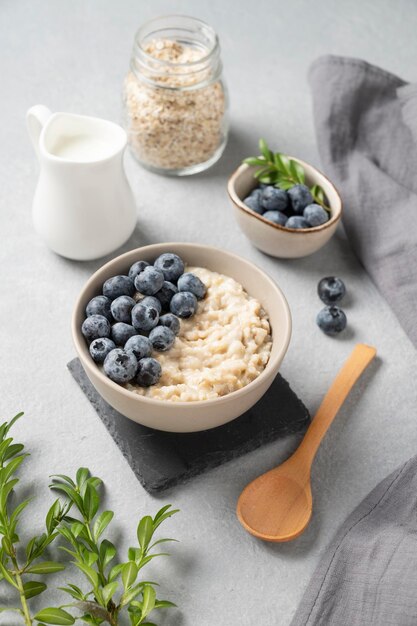 Oatmeal porridge with blueberries in bowl on a blue background with berries and milk The concept of a delicious nutritious and healthy breakfast