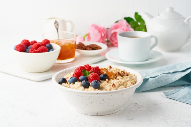 Oatmeal porridge with blueberry, raspberries, jam and nuts, top view. Breakfast with berries