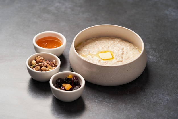 Oatmeal porridge with raisins, honey and nuts in a bowl