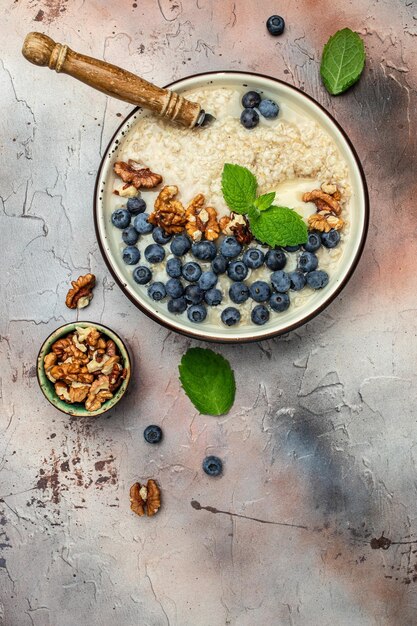 소박한 나무 보드에서 건강한 아침 식사를 위해 잘 익은 블루베리를 곁들인 오트밀 죽 디톡스와 건강한 슈퍼푸드 그릇 개념