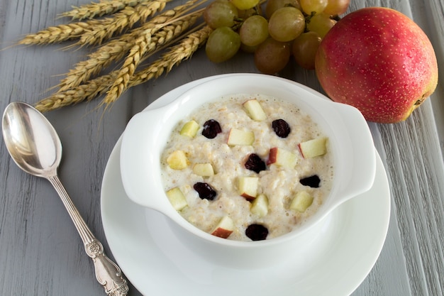 Farina d'avena con mela e uvetta nel piatto bianco