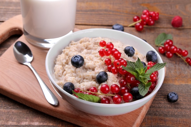 Oatmeal with berries and milk in a bowl on a brown wooden table. breakfast. healthy food.