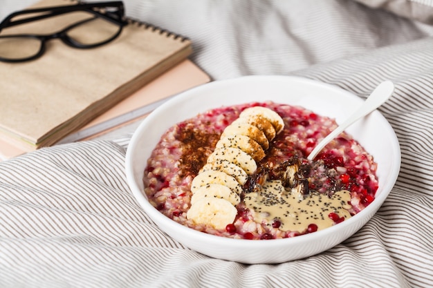 Oatmeal with berries, peanut butter, banana and chia in a white bowl.