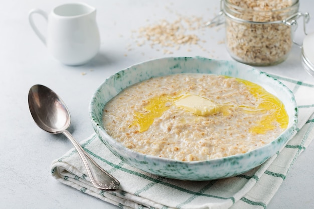 Foto farina d'avena con burro in un piatto di ceramica su una pietra chiara o cemento.