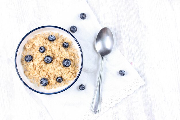 Foto farina d'avena con mirtilli freschi. dieta alimentare - porridge di farina d'avena in un piatto con un cucchiaio.