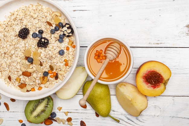 Oatmeal with fruit and honey on a white wooden table