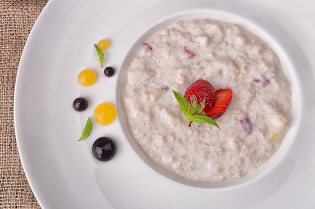 Oatmeal with strawberries and pieces of fruit on a plate