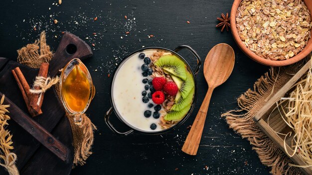 Oatmeal with yogurt and fruits and berries Kiwi blueberry raspberry On a wooden background Top view Free space for text